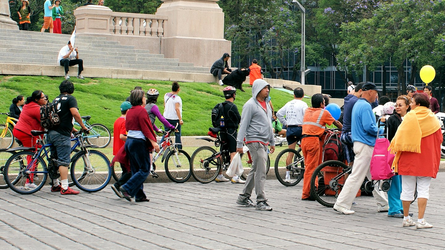 Group of people with bicycles standing on an urban plaza.