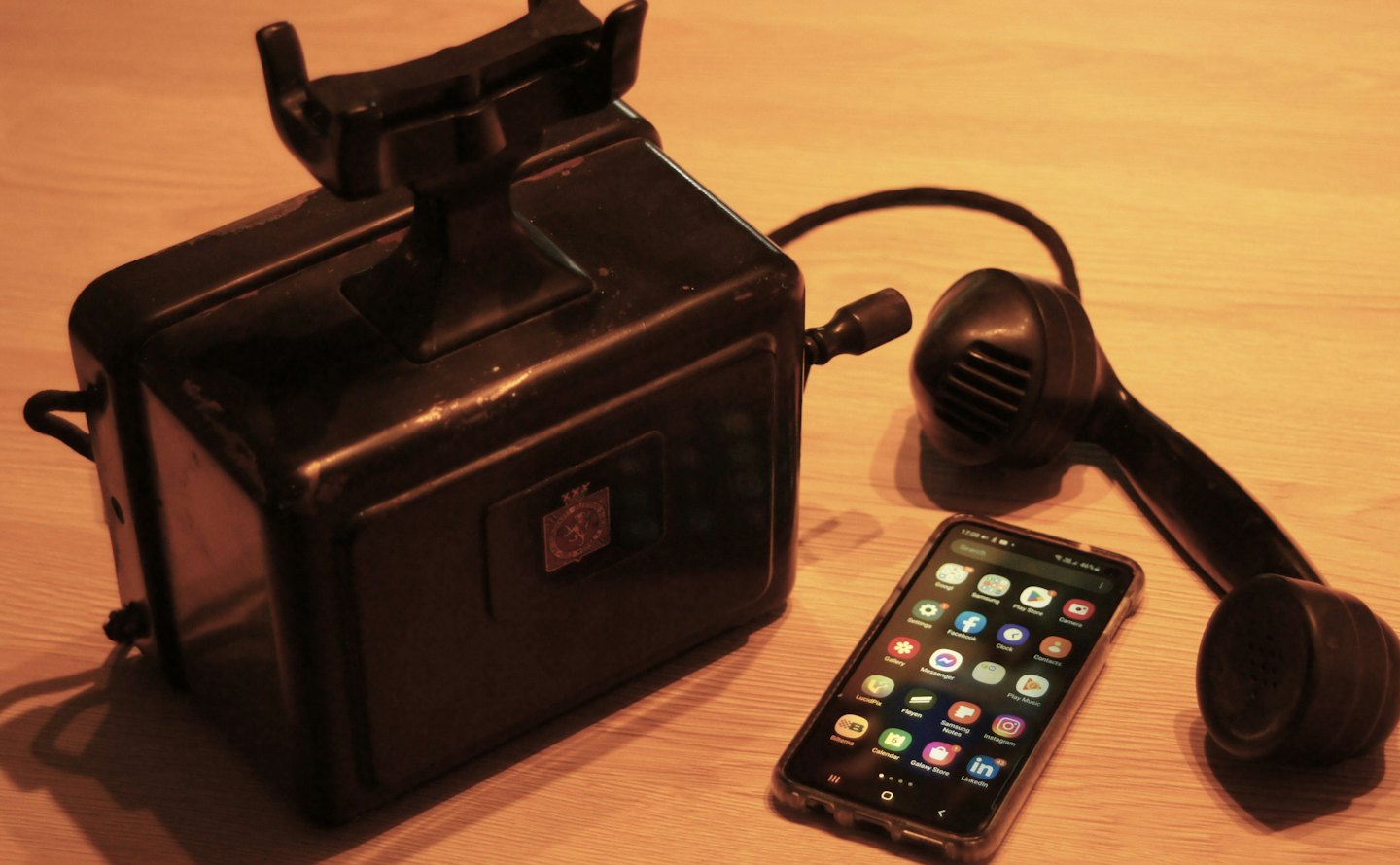 Antique telephone and modern smartphone on a wooden table.