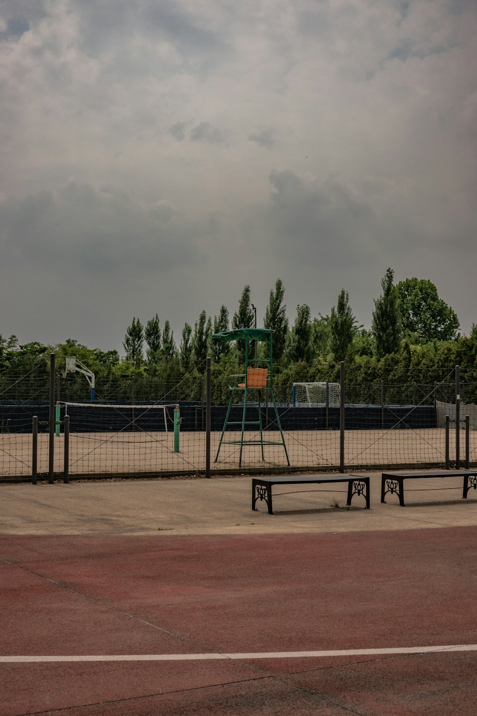 Empty tennis court with a basketball hoop and soccer goal.