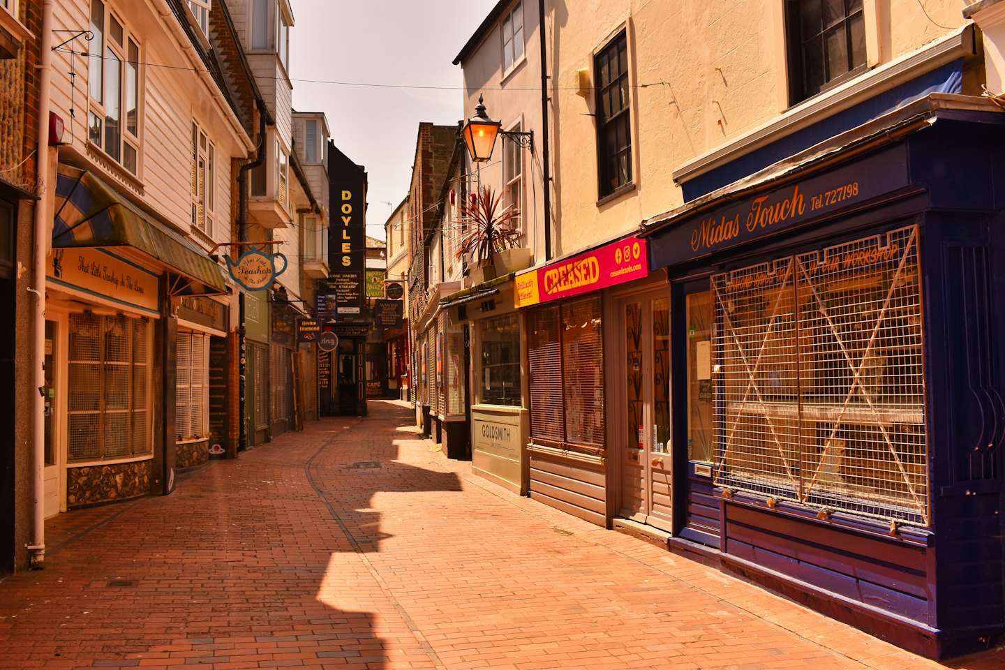 Quiet pedestrian alleyway lined with closed independent shops.