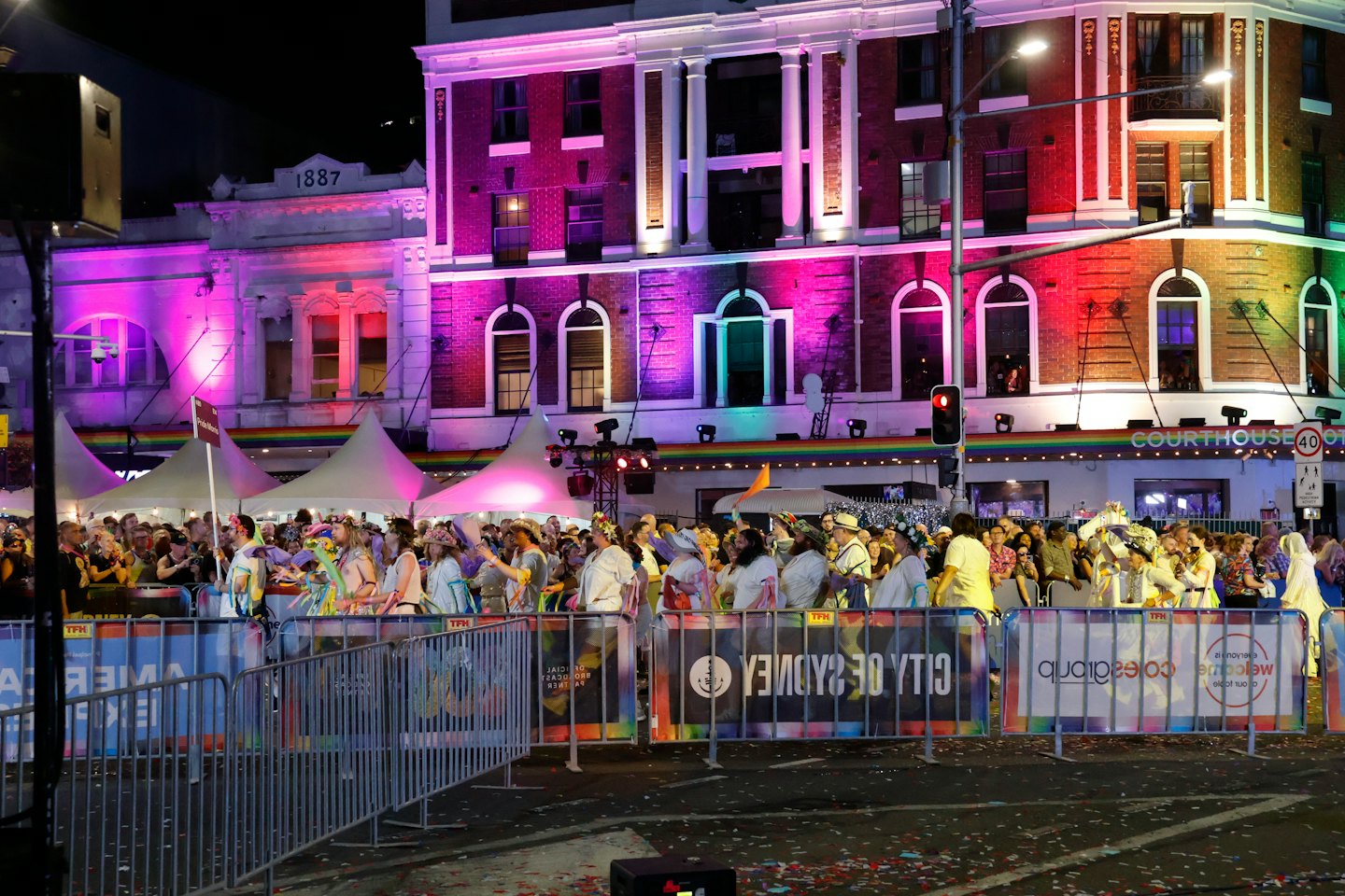 People celebrating at an outdoor festival with illuminated brick buildings.