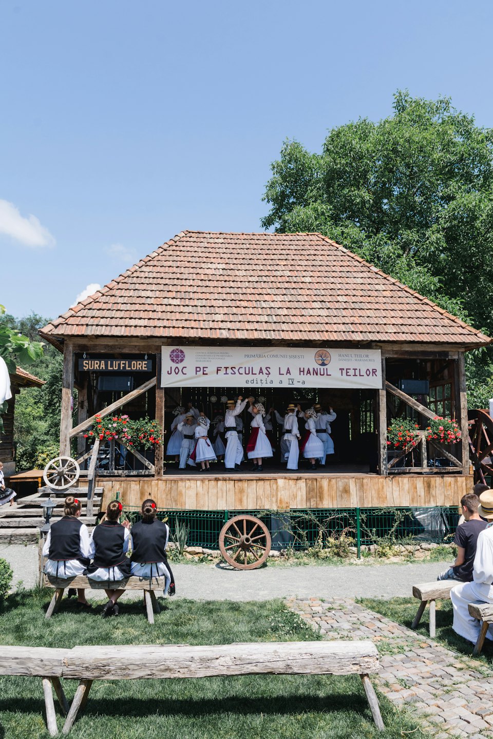 People perform a traditional dance on a wooden stage.