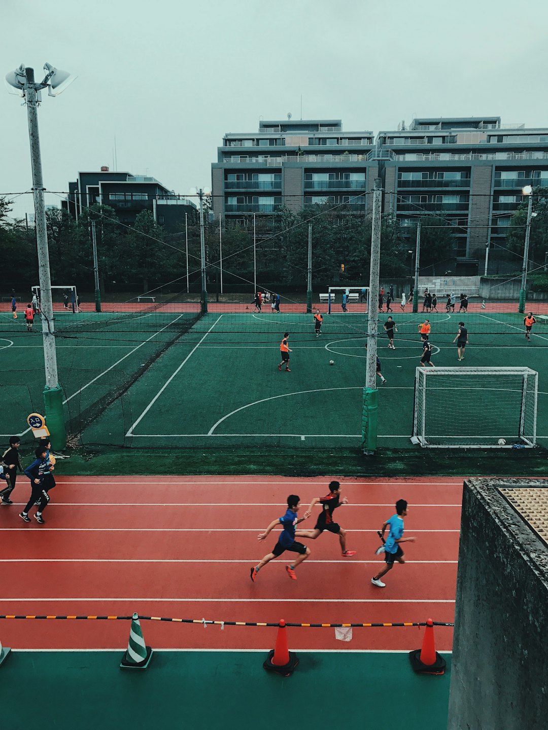 Children play football and run on a sports field.