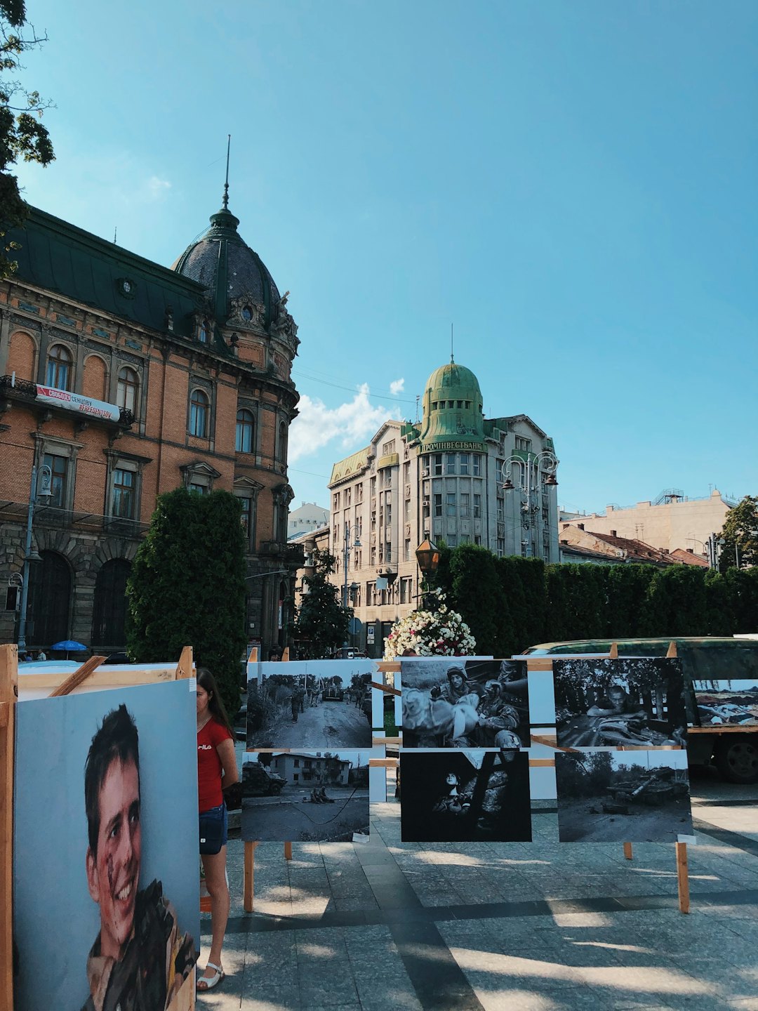 Woman walks past a outdoor photography exhibit in a city square.