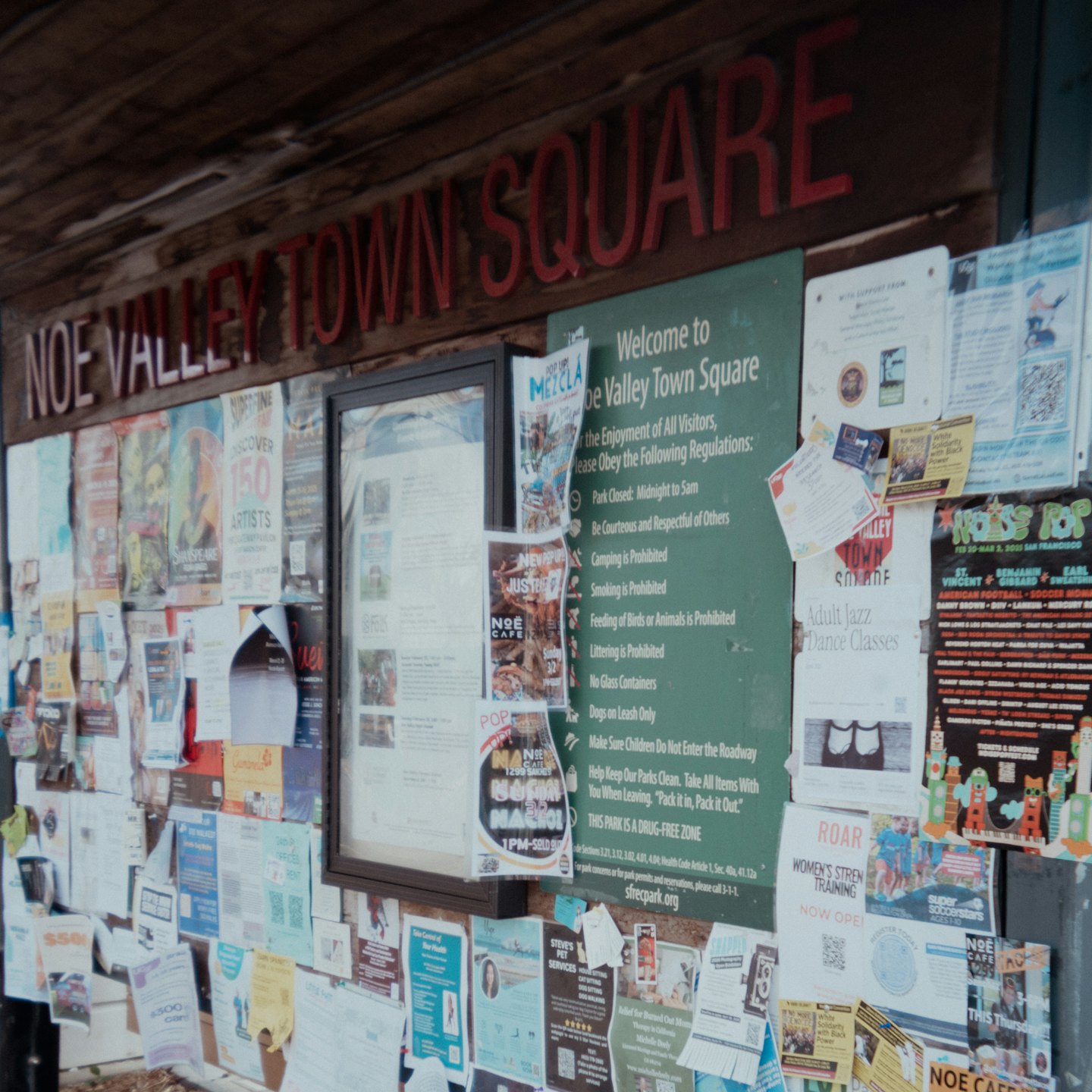 Flyers cover a wooden bulletin board at Noe Valley Town Square.